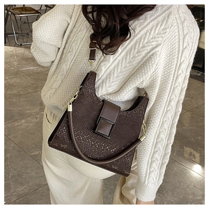 Detail of dark brown faux crocodile shoulder bag with golden buckle on cable knit sweater