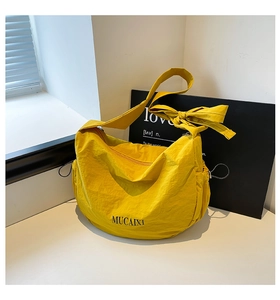 Sac à bandoulière en nylon jaune avec nœud sur la sangle et poches latérales à cordon
