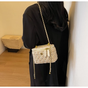 Detailed back view of a mini tweed crossbody bag with gold chain strap on a model