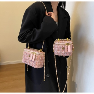 Detailed view of pink tweed chain vanity bag with gold flower decor and metal strap