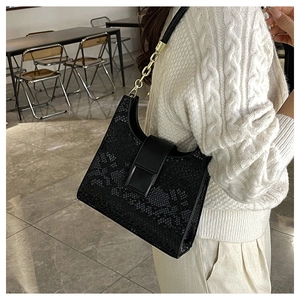 Detail of black snake-embossed shoulder bag with gold chain strap on model