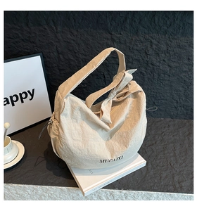 Détail du sac beige en nylon avec grand nœud sur la bandoulière et détails de serrage