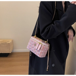 Detail of pink tweed crossbody box bag with metal chain and camellia flower ornament