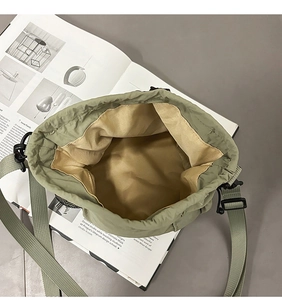 Detail of army green nylon bucket bag with yellow lining and adjustable woven strap