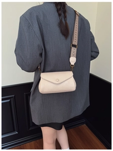 Dettaglio di una borsa a tracolla beige in pelle con ampia tracolla etnica in tessuto