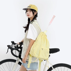 Detail of light yellow drawstring backpack with front pocket and side racket storage