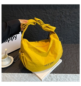 Détail du sac hobo en nylon jaune avec un grand nœud décoratif sur la bandoulière