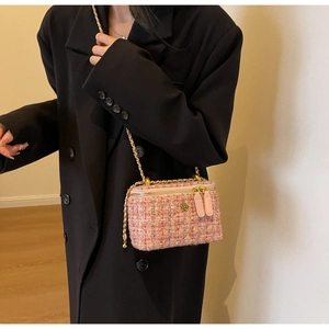 Detailed view of pink tweed bucket bag with gold flower charm on black blazer