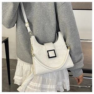 Détail d'un sac bandoulière blanc gaufré serpent avec une boucle décorative carrée noire