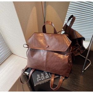 Detailed macro view of deep coffee brown faux leather backpack with vintage texture