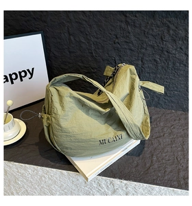 Détail du sac hobo vert clair en nylon avec logo MUCAIXI et texture plissée