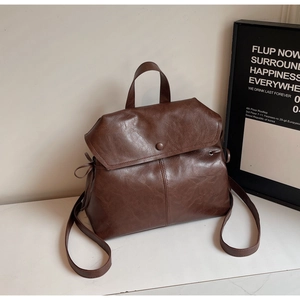 Detail of vintage brown leather backpack with drawstring and top handle on marble surface