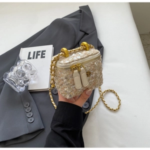 Detailed close-up of a mini tweed bucket bag with a golden camellia flower zipper puller