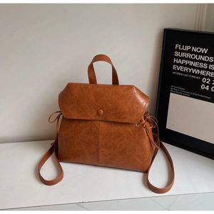 Detail of vintage brown PU leather backpack with buckle flap and drawstring side accents