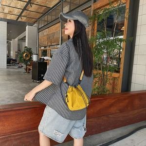 Mini yellow nylon drawstring crossbody bag styled with casual street fashion outfit