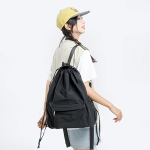Minimalist black drawstring backpack with front zipper pocket and lightweight nylon fabric