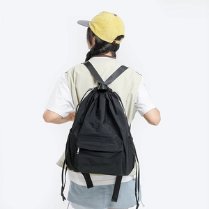 Rear view of model wearing a black nylon drawstring backpack with large capacity