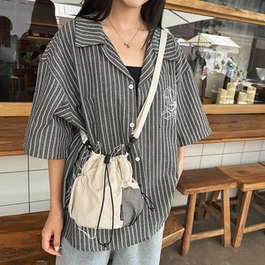 Detail of cream nylon bucket bag with side mesh pocket and adjustable strap worn by model