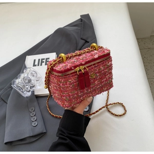 Detailed macro of pink tweed texture with gold flower hardware on chain bag