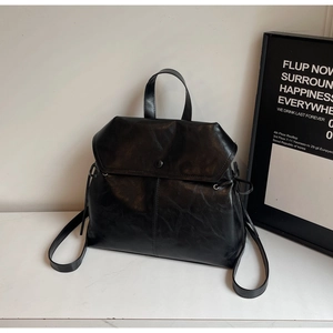 Detail of vintage black faux leather backpack with distressed texture and drawstring