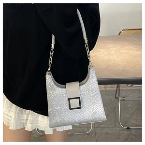 Détail du sac bandoulière argenté à texture écailles avec boucle noire et chaîne dorée