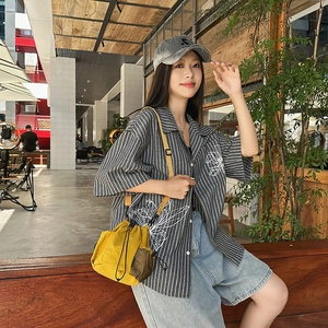 Close-up of a yellow nylon bucket bag with adjustable drawstrings in an urban setting