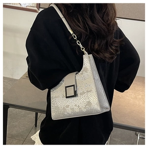 Silver snakeskin textured shoulder bag with metal chain strap worn by a model
