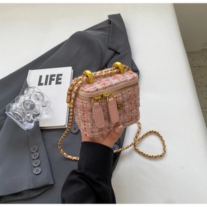 Detail of pink tweed texture and golden chain on a vintage-style vanity crossbody bag