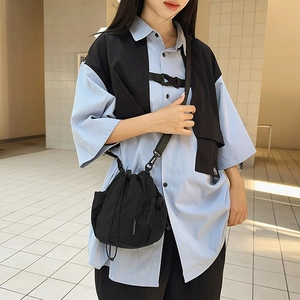 Detail of a black nylon drawstring crossbody bag featuring a mesh side pocket and logo