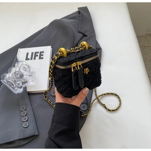 Close-up of black tweed mini chain bag with gold ring handle and metal flower charm