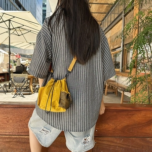 Detailed back view of a yellow nylon bucket bag styled with casual outdoor summer wear