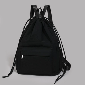 Front detail of black drawstring backpack with smooth nylon texture and silver zipper pocket