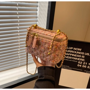 Detailed close-up of a pink tweed mini chain bag with a gold camellia floral charm