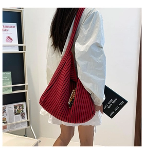 Detail der rot-schwarz gestreiften Stricktasche mit dekorativer Perlenquaste