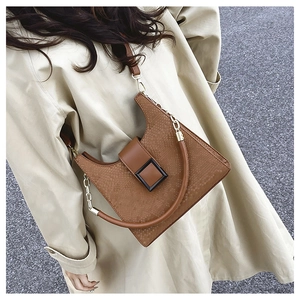 Brown snakeskin-textured handbag with gold hardware styled on a beige trench coat