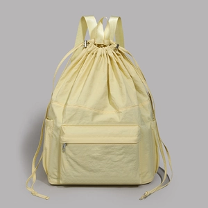 Detail view of lightweight pale yellow drawstring backpack with nylon texture and front pocket