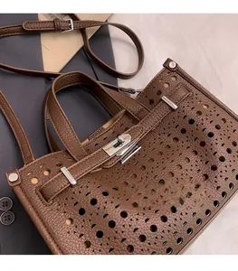 Close-up of brown pebbled leather tote with geometric cutouts and silver turn-lock clasp