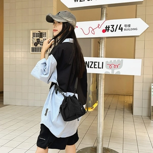 Outdoor shot of a black nylon drawstring bucket bag paired with a casual outfit