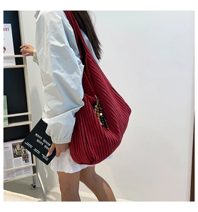 Detail of red and black striped canvas tote bag with colorful beaded charm accessory