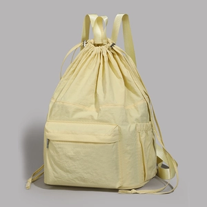 Detail of light yellow drawstring backpack showing waterproof nylon texture and front pocket