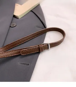 Close-up of adjustable brown litchi pattern leather shoulder strap with silver buckle