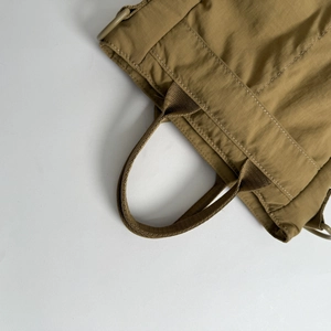 Detailed close-up of khaki nylon tote bag reinforced stitching and D-ring attachment