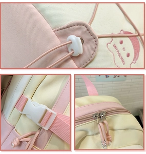 Detail view of pink and beige backpack featuring cute embroidery and metal zippers