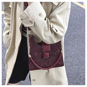 Detail of burgundy snakeskin texture handbag with a metallic square buckle on a model