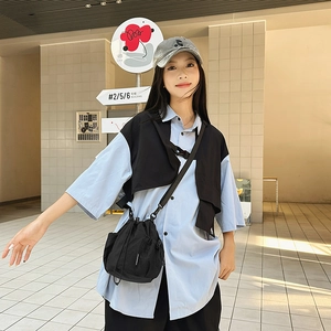 Detail of minimalist black nylon bucket bag with side mesh pocket on a streetwear model