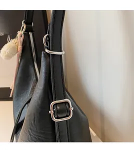 Detail of black leather tote bag with adjustable shoulder strap and silver buckle