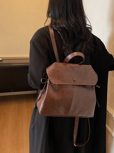 British style vintage brown leather backpack worn by a model in a warm indoor setting