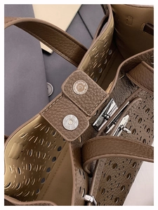 Detail of brown litchi grain leather tote featuring laser cutouts and silver hardware