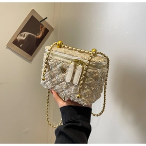 Macro detail of beige tweed box bag with metal camellia logo and woven chain strap