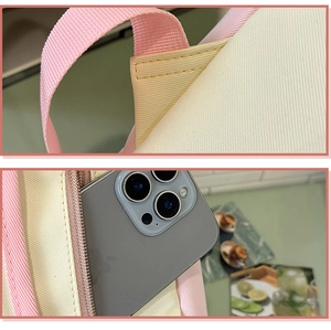 Macro details of pink backpack showing reinforced stitching and a side pocket for smartphones